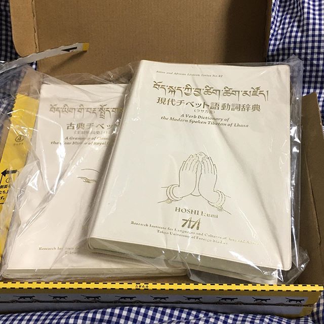 長らく探していた口語チベット語の辞書『現代チベット語動詞辞典 (ラサ方言)』が手に入った。17〜8年前に星泉さんが著して今も評価の高い辞書だが、気づいたときには在庫が無くなっていた。もともと発行部数が少なかったので古書として出てくることも滅多にない。たまにヤフオクとかに高額で出品されていたようで、少々高くても落札したかったが行き当たったことがなかった。それが偶然、数年前に増刷されていたと知ったのはほんの4日前。また乗り遅れたか、と思ったけど、ダメ元で問い合わせみてみたら「在庫あり」とのこと。さらに、オマケと言う訳ではないが、『古典チベット語文法：『王統明鏡史』(14世紀) に基づいて』と言う星泉さんの新刊も配布されていて、どちらも無料でいただけるとのこと。早速「東京外国語大学アジア・アフリカ言語文化研究所多言語・多文化共生に向けた循環型の言語研究体制の構築（LingDy3）事務局」と言う恐ろしく長い名前の配布を元に申し込んだ。どういうわけか研究者・大学関係者と勘違いされて送料も免除と連絡があった。チベット研究をやっている知り合いの大学教授と共同編集した大学の刊行物がいくつかあるので、僕まで研究者だと思われたのだろう。チベット関係に限らず、大学や研究所はどこも予算が逼迫している昨今、配布元がそう言ってくれてもこれ幸いと無料でもらうわけにはいかない。丁寧にお断りして、着払いで送っていただいた。今朝届いて、箱を開けるのももどかしくワクワクしながら手に取って、辞書と文法書を開いた。日本のチベット語研究は仏教を通じて始まったので、古い辞書や文法書はどちらかと言うととっつきにくいものが多いが、送ってもらった2冊はずいぶん様相が違っている。かといって旅行者用の簡易な会話手帳のようなものでももちろんない。星泉さんのお母さんの星三千代さんのチベット語入門書も読んだことがあるが、其処此処に「受け継がれた伝統」のようなものを感じる。 (from Instagram)